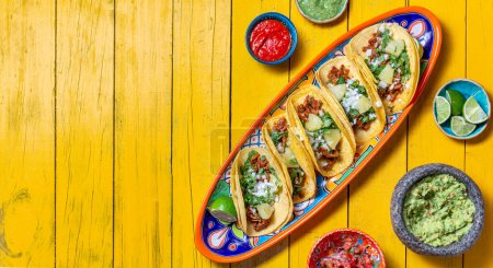 Téléchargez les photos : Fond mexicain avec tacos al pastor et sauces mexicaines. Fond en bois jaune, espace de copie, vue de dessus. - en image libre de droit