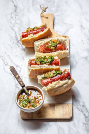 Photo for Chilean and Argentinian food. Traditional choripan with spicy pebre, chorizo sandwich with chorizo sausages and bread - Royalty Free Image