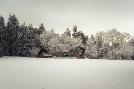 Photo for Snowy winter landscape with forest, meadow and a small farm - Royalty Free Image