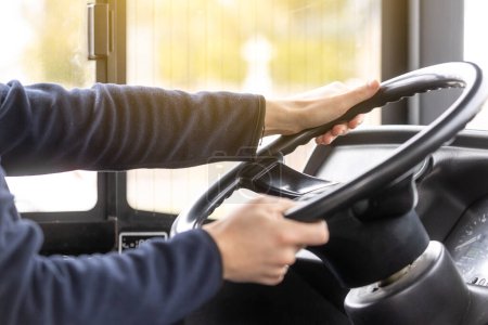 Close up of bus driver hands on a steering wheel during driving the bus, public transport concept