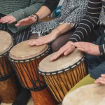 Women playing on a djembe drums during music therapy, drumming healing