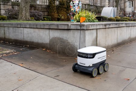 Foto de Un robot de reparto de comida de Starship está conduciendo en la acera en el campus de la Universidad de Pittsburgh en Pittsburgh, PA, EE.UU. el 11 de enero de 2020. Los Robots están entregando comida de cuatro restaurantes del campus. - Imagen libre de derechos