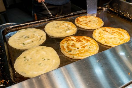 Taiwanese street foods - Green Onion Pancake on the hot plate at a street food vendor in the night market in Taipei, Taiwan