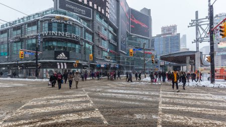 Photo for Toronto, Canada - February 7, 2018: People crossing the Yonge-Dundas intersection in the snow in Toronto. - Royalty Free Image