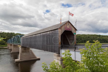 Foto de NEW BRUNSWICK, CANADÁ - 6 de agosto de 2017: Florenceville Bridge en New Brunswick, Canadá. Construido en 1907, este puente cubierto tiene una longitud de 46,9 m. y combinado con unas cerchas de acero. - Imagen libre de derechos