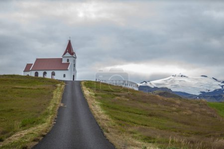 Téléchargez les photos : Une route menant à l'église d'Ingjaldsholl avec montagne de neige en arrière-plan à Hellisandur, à la frontière du parc national Snaefellsjokull, péninsule de Snaefellsnes, Islande. - en image libre de droit
