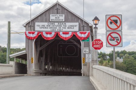 Foto de NUEVA BRUNSWICK, CANADÁ - 6 de agosto de 2017: Entrada del puente cubierto Hartland en New Brunswick. Este puente de 390 m (1.282 pies) se inauguró en 1901, el puente cubierto de madera más largo del mundo. - Imagen libre de derechos