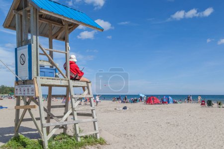 Téléchargez les photos : COBOURG (ONTARIO), CANADA - LE 10 JUILLET 2016 : Une femme sauveteuse est en service à Victoria Beach, à Cobourg, en Ontario, le 10 juillet 2016 Cobourg a l'une des meilleures plages de l'Ontario. - en image libre de droit