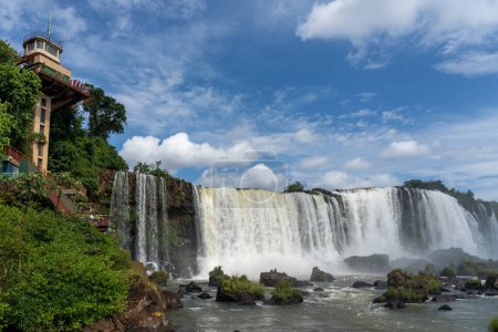 Téléchargez les photos : La tour d'observation avec des personnes non reconnues et vue sur les chutes d'Iguazu dans le NP dans l'État du Parana, au Brésil. Le NP d'Iguazu est une attraction partagée entre le Brésil et l'Argentine. - en image libre de droit
