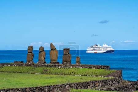 Téléchargez les photos : Île de Pâques, Chili - 5 mars 2023 : Statues Moai sur Ahu Vai Ure avec un bateau de croisière en arrière-plan au complexe Tahai sur l'île de Pâques au Chili. Tahai est un complexe près du village Hanga Roa. - en image libre de droit