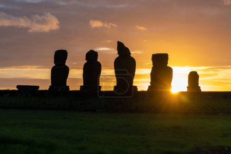 Téléchargez les photos : Coucher de soleil derrière les statues de moai sur Ahu Vai Ure dans le complexe de Tahai sur l'île de Pâques (Rapa Nui) au Chili. Tahai est un complexe archéologique formé par trois plates-formes cérémonielles près du village Hanga Roa. - en image libre de droit