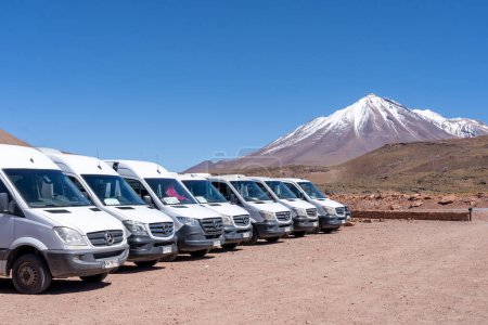 Téléchargez les photos : San Pedro de Atacama, Chili - Février 23, 2023 : minibus tour blanc sur le parking à Red Rocks (Piedras Rojas) avec Vulcano Miniques en arrière-plan dans le désert d'Atacama, Chili. - en image libre de droit
