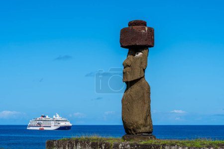 Foto de Isla de Pascua, Chile - 5 de marzo de 2023: La estatua moai con sombreros y ojos de coral restaurados en Ahu Ko Te Riku con un crucero al fondo en el complejo Ahu Tahai. Isla de Pascua (Rapa Nui), Chile - Imagen libre de derechos