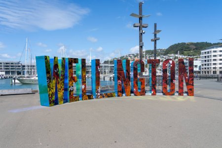 Foto de Wellington, Nueva Zelanda - 11 de febrero de 2024: WELL _ NGTON signo escultórico en el paseo marítimo en Wellington, Nueva Zelanda. - Imagen libre de derechos