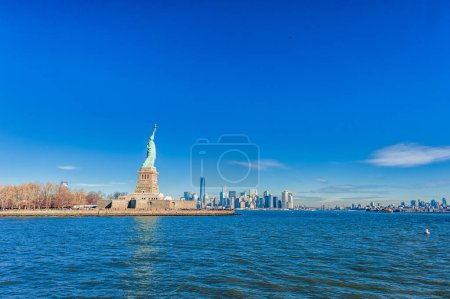 Téléchargez les photos : Statue de la Liberté sur Liberty Island et New York Manhattan avec gratte-ciel et ciel bleu - en image libre de droit