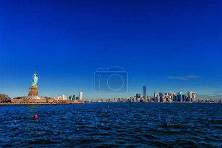 Téléchargez les photos : Statue de la Liberté sur Liberty Island et New York Manhattan avec gratte-ciel et ciel bleu - en image libre de droit