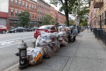Foto de Manhattan, NYC - October 07, 2019: DSNY workers collect trash on a city street. New York Department of Sanitation is responsible for garbage. Truck on the street - Imagen libre de derechos