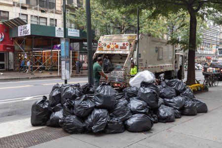 Foto de Manhattan, NYC - October 08, 2019: DSNY workers collect trash on a city street. New York Department of Sanitation is responsible for garbage - Imagen libre de derechos