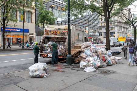 Foto de Manhattan, NYC - October 08, 2019: DSNY workers collect trash on a city street. New York Department of Sanitation is responsible for garbage - Imagen libre de derechos
