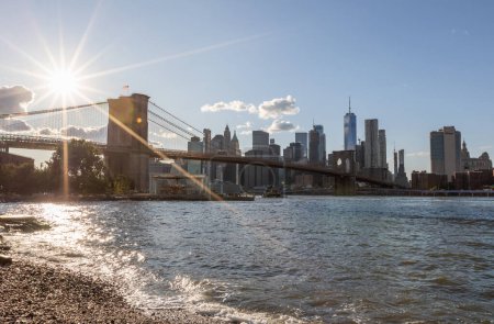 Téléchargez les photos : Brooklyn Bridge, East River and Lower Manhattan in Background. NYC Skyline. Bright Sunny Day and Sunlight. Dumbo. Sightseeing Place Among Locals and Tourists in NYC. - en image libre de droit