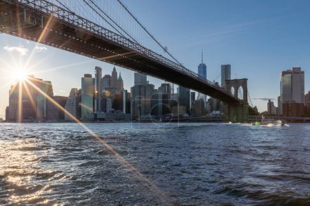 Téléchargez les photos : Brooklyn Bridge, East River and Lower Manhattan in Background. NYC Skyline. Bright Sunny Day and Sunlight. Dumbo. Sightseeing Place Among Locals and Tourists in NYC. - en image libre de droit