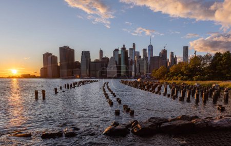 Photo for Beautiful Sunset and Lower Manhattan skyline with East River and New York City. Twilight with Reflections and Abandoned Pier at Sunset from Brooklyn Bridge Park - Royalty Free Image
