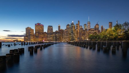 Photo for Beautiful Sunset and Lower Manhattan skyline with East River and New York City. Twilight with Reflections and Abandoned Pier at Sunset from Brooklyn Bridge Park - Royalty Free Image