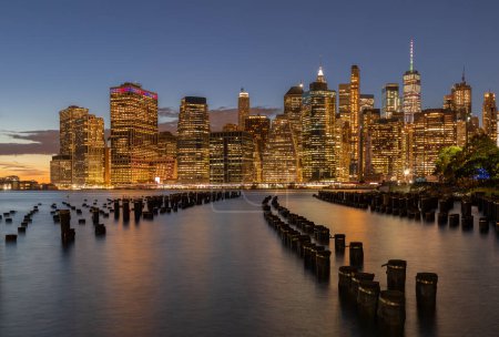 Téléchargez les photos : Beautiful Night Light and Lower Manhattan skyline with East River and New York City. Twilight with Reflections and Abandoned Pier at Sunset from Brooklyn Bridge Park - en image libre de droit