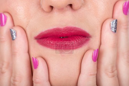 Téléchargez les photos : Curieux visage de femme avec les lèvres et les doigts avec des ongles polonais. Séance photo Studio. - en image libre de droit