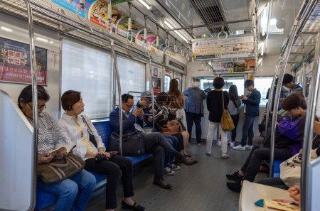 Téléchargez les photos : TOKYO, JAPAN - OCTOBER 30, 2019: Tokyo Metro Train and People sitting in the car. Seibu Shinjuku Station - en image libre de droit