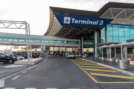 Foto per ROMA, ITALIA - 22 OTTOBRE 2019: Roma aeroporto internazionale Leonardo da Vinci Fiumicino esterno con auto. Area di partenza. Terminal 3 sullo sfondo - Immagine Royalty Free