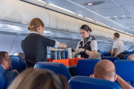 Photo for ROME, ITALY - OCTOBER 23, 2019: Aeroflot Russian Airlines Cabin Crew Serving Food and Beverages during the flight to Moscow from Rome, Italy. - Royalty Free Image