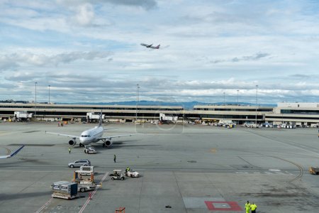 Téléchargez les photos : SAN FRANCISCO, CALIFORNIE - 04 AVRIL 2019 : Aéroport international de San Francisco. United Airlines Boeing est un service au sol et de taxation en arrière-plan. American Airlines décolle - en image libre de droit