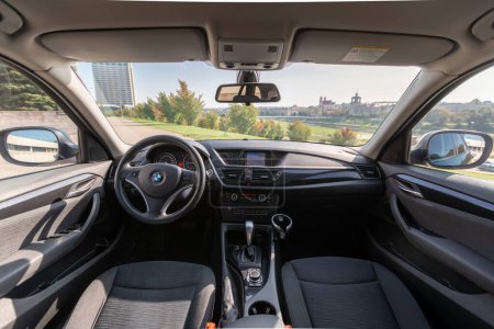 Téléchargez les photos : Interior of BMW X1 2012 Year compact sport utility vehicle. Beautiful Sunny Cityscape Background. - en image libre de droit
