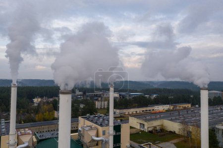 Téléchargez les photos : Smoking chimneys on the late autumn sky background. Heating season. The view of chimneys tops of the thermal station. - en image libre de droit