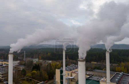 Foto de Smoking chimneys on the late autumn sky background. Heating season. The view of chimneys tops of the thermal station. - Imagen libre de derechos
