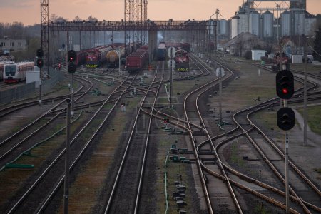 Foto de Red ferroviaria en Lituania. Radviliskis es una conocida capital ferroviaria de Lituania. Hermosa luz del atardecer y coches en el fondo. - Imagen libre de derechos