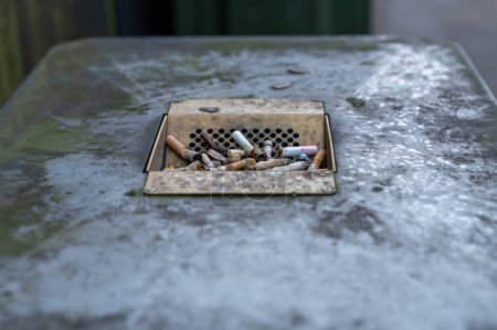 Foto de Cigarette Butts in ashtray on the public trash can in England, London. Dirty - Imagen libre de derechos