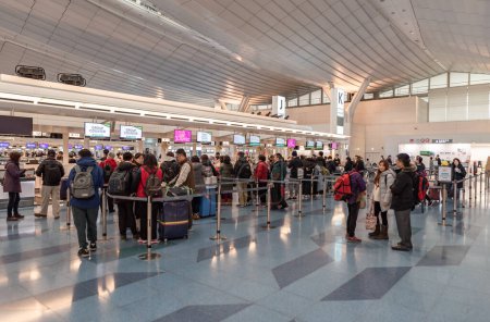 Foto de Aeropuerto Internacional de Tokio Haneda. Zona de salida con mostradores de check-in y personas. - Imagen libre de derechos