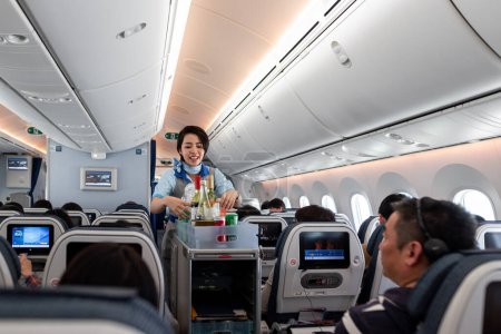 Téléchargez les photos : Japan ANA Airlines and Boeing 787 Dreamliner interior with People And ANA Cabin Crew Members working for passengers. - en image libre de droit