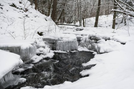 Téléchargez les photos : Snowy Winter Landscape with River in Forest. Flowing Water and Breaking Ice. Nature - en image libre de droit