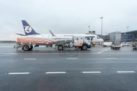 Téléchargez les photos : Aéroport international de Riga avec Pologne Avion et camion-citerne en arrière-plan. Lettonie - en image libre de droit