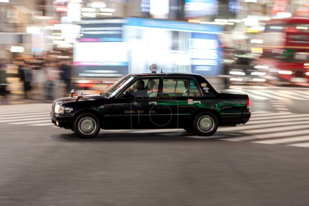 Téléchargez les photos : District de Shibuya à Tokyo. Intersection célèbre et la plus achalandée au monde, Japon. Shibuya Crossing. Panoramique floue noir Taxi - en image libre de droit