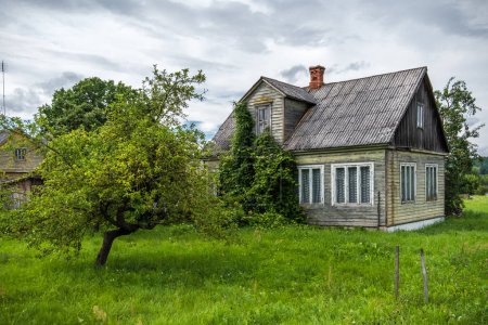 Foto de ZAPYSKIS, LITHUANIA - 13 de agosto de 2017: Zapyskis Country en Kaunas District, Lituania. Antigua casa de madera con jardín de manzanos en el patio trasero. - Imagen libre de derechos