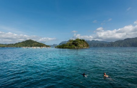 Téléchargez les photos : CORON, PHILIPPINES - 30 JANVIER 2018 : Les gens nagent dans l'eau de mer. CYC île et plage en arrière-plan. Coron, Philippines. - en image libre de droit