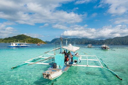 Téléchargez les photos : CORON, PHILIPPINES - 30 JANVIER 2018 : Des bateaux attendent les touristes. CYC île et plage en arrière-plan. Coron, Philippines. - en image libre de droit