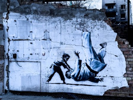 Foto de Borodyanka, Región de Kiev 02.05.2023 Trabajo mural Banksys en una pared dañada junto a edificios residenciales completamente destruidos. Foto de alta calidad - Imagen libre de derechos