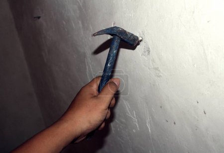 clavando una pared, sosteniendo un martillo