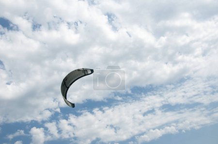 Photo for Henichesk, Ukraine - July 12, 2021: Kitesurfing. Seascape with kitesurfer in waves. Surfer in wetsuit doing trick in air against sea. Kitesurfing athlete on kite with board. - Royalty Free Image