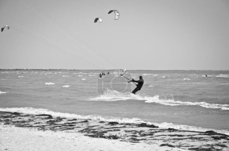 Photo for Henichesk, Ukraine - July 12, 2021: Seascape kitesurfer waves. Surfer in wetsuit do trick. Kitesurfing athlete on kite with board. Foiling kiteboarding kitesurfing kiteboarder in ocean. Kitesurfing. - Royalty Free Image